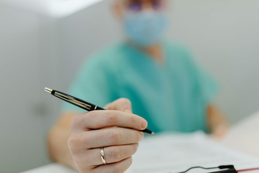 pexels photo 6627921 6627921 Close-up of a medical professional in scrubs writing with a pen, showing focus on hand and pen.